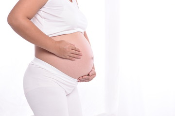  A beautiful pregnant woman holding her stomach affectionately at home.