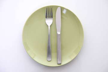 白い木製テーブルに置かれた緑の皿とカトラリーによる食事終了の合図