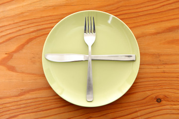 木製のテーブルに置かれた緑の皿とカトラリーによる次の料理を待機の合図