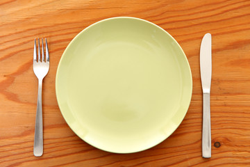 木製のテーブルに置かれた緑の皿とカトラリー