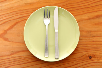 木製のテーブルに置かれた緑の皿とカトラリーによる食事終了の合図