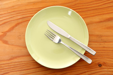 木製のテーブルに置かれた緑の皿とカトラリーによる食事終了の合図