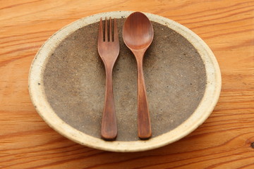 木製のテーブルに置かれた土の皿と木製カトラリー