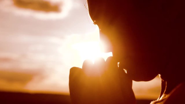 the girl prays. Girl folded her hands in prayer silhouette at sunset. slow motion video. Girl folded her hands lifestyle in prayer pray to God. girl praying asks forgiveness for sins of repentance