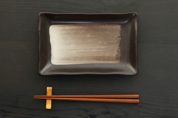 黒いテーブルに置かれた魚皿と箸