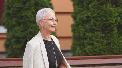 Confident stylish old woman sitting with crossed legs. Confidence and success concept. Rest time. - Powered by Adobe