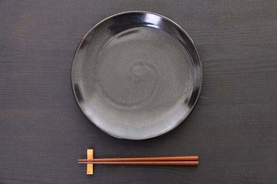 黒い木製テーブルに置かれた黒い皿と箸