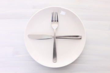 白い木製テーブルに置かれた白い皿とカトラリーによる次の料理を待機の合図