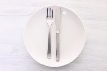 白い木製テーブルに置かれた白い皿とカトラリーによる食事終了の合図