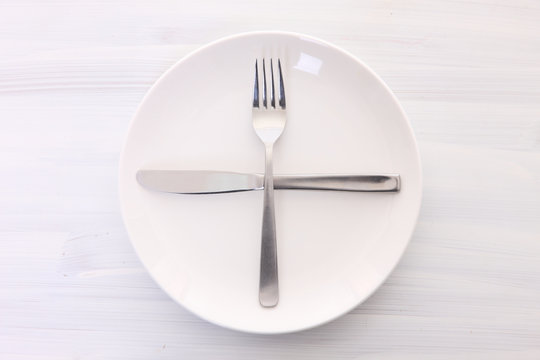 白い木製テーブルに置かれた白い皿とカトラリーによる次の料理を待機の合図