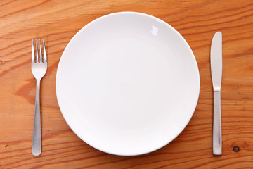 木製テーブルに置かれた白い皿とカトラリー