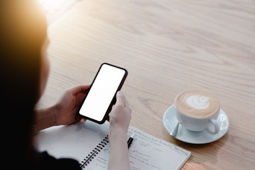Mockup image of a woman holding mobile phone with blank black screen in modern loft cafe