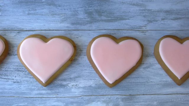 Heart shaped cookies with pink icing. Row of fresh desserts on grey wood. Valentines holiday background.