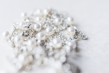 Silver jewelery with diamonds and pearls in the defocus on a white background