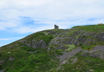 Fototapeta na wymiar looking up from the hiking path on the bottom of Signal Hill covered with lush green grass towards the tower, St John's Newfoundland Canada