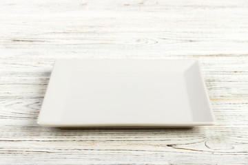 Perspective view. white square plate on a wooden table