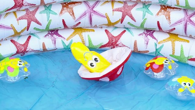 Inflatable colourful kid toys floating in an inflatable swimming pool with shallow water