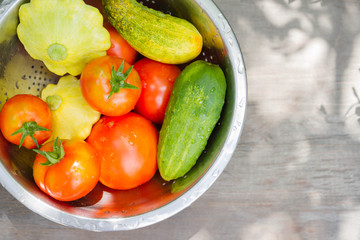 Tomato, cucumber, zucchini, patisson in an iron pan on a wooden table. Concept of a healthy diet, dietetic vegetables. Harvesting