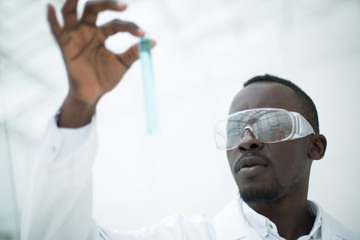 close up. Serious Clinician looking at flask with blue liquid