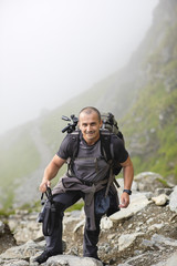 Photographer with backpack and camera hiking on a mountain trail