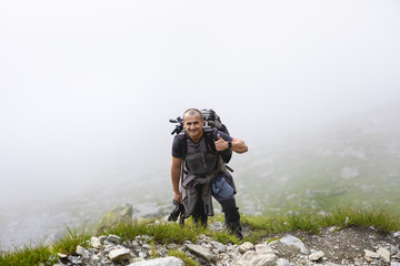 Photographer with backpack and camera hiking on a mountain trail