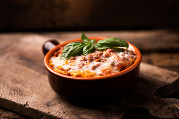 Traditional lasagne in a casserole dish on wooden table - obrazy, fototapety, plakaty