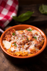 Traditional lasagne in a casserole dish on wooden table