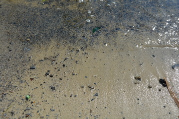 Yellow river sand with black small stones and a river wave of the Dnieper