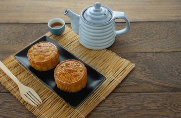Close up image of food dessert decorations Chinese Moon Festival background concept.Accessories cake & tea cup and bamboo on modern rustic wooden plank.Free space for creative design mock up.