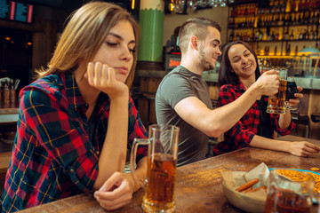 people, leisure, friendship and communication concept - happy friends drinking beer, talking and clinking glasses at bar or pub