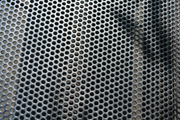 Metal mesh, background, with round identical holes, metal structure with shadow and light