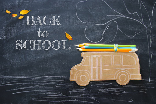 Back to school concept. Top view image school bus and pencils over classroom blackboard background.