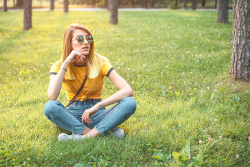 Fototapeta premium Woman sitting on the grass at sunset