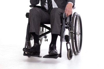 Obraz premium Cropped picture of disbaled man insuit. Studio shot of man sitting in wheelchair wearing fancy business outfit.