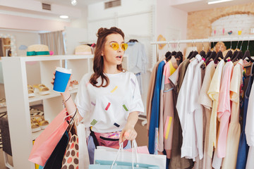 Coffee and bags. Modern fashion designer holding her cup of coffee and many bags with purchases