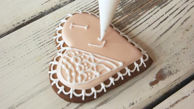 Decoration of frosted cookie for Valentines Day. Making ornamentation on heart-shaped biscuit. I love you inscription. Edible symbol of love.