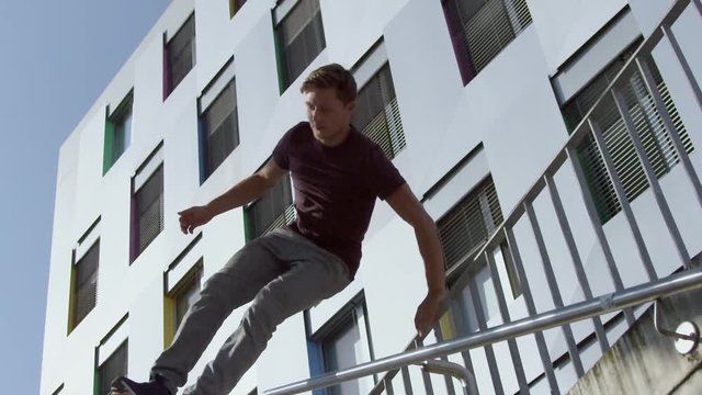 Parkour runner jumping over the railing and running down stairs in slow-motion.