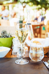 Wine and water at the table. Outdoor Italian restaurant terrace. Concept of summer authentic meal