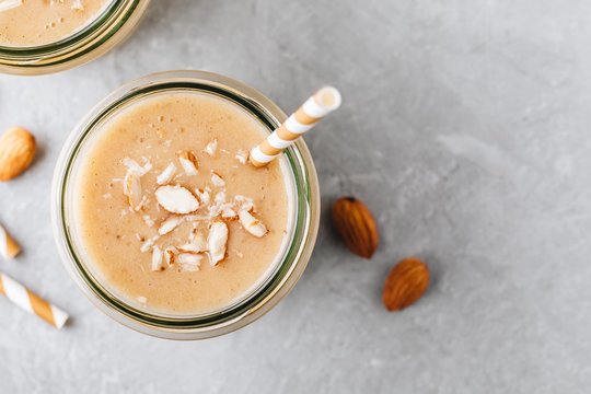 Banana almond smoothie with cinnamon and oat flakes and coconut milk in glass jars