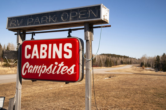 A Red Hanging Neon Roadside Sign Says Cabins and Campsites