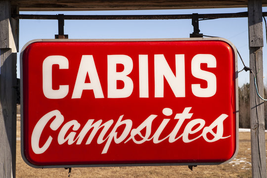 A Red Hanging Roadside Sign Says Cabins and Campsites