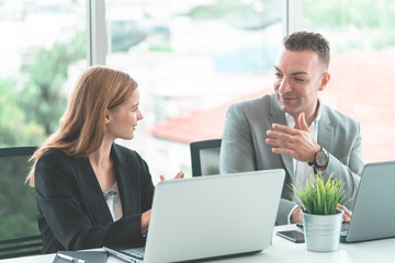 Male boss is discussing with female worker in happy manner