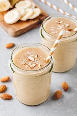 Poster Milkshake Banaan-amandel-smoothie met kaneel en havervlokken en kokosmelk in glazen potten