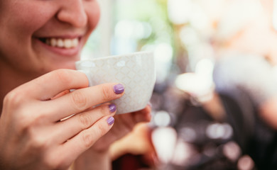 Junge Frau hält Kaffeetasse in der Hand und lächelt, Ausschnitt, Italien