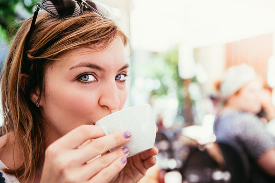 Junge Frau trinkt Kaffee und blickt in die Kamera, Italien