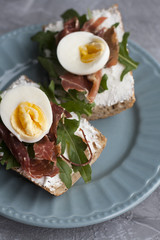 Sandwiches with whole grain bread, homemade cheese, arugula, ham and egg. Healthy snack.