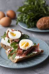Sandwiches with whole grain bread, homemade cheese, arugula, ham and egg. Healthy snack.