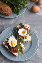 Sandwiches with whole grain bread, homemade cheese, arugula, ham and egg. Healthy snack.