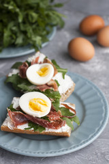 Sandwiches with whole grain bread, homemade cheese, arugula, ham and egg. Healthy snack.
