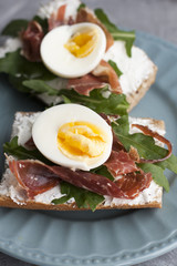 Sandwiches with whole grain bread, homemade cheese, arugula, ham and egg. Healthy snack.